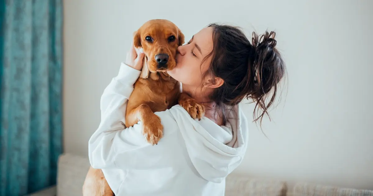 Woman kissing her puppy