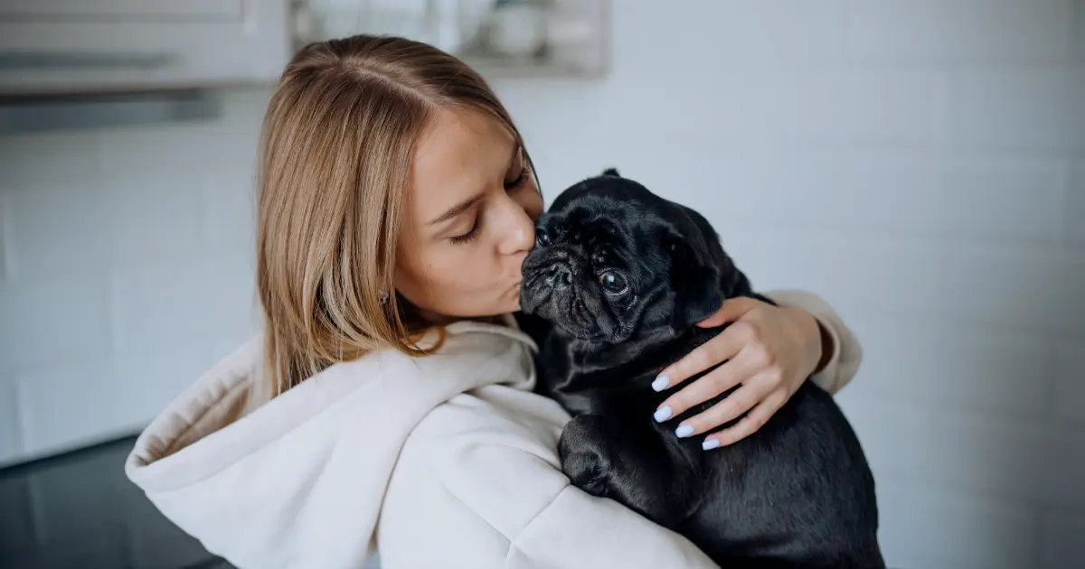 Lady kissing her black pug